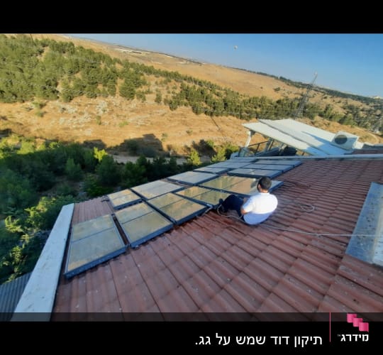 פאנלים סולאריים על גג רעפים עם אדם יושב לידם